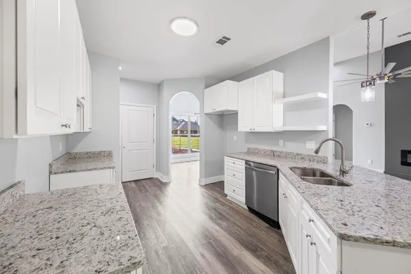 a large kitchen with granite countertop a white stove top oven and white cabinets