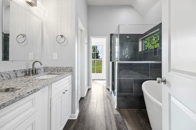 a bathroom with a granite countertop sink a mirror and shower