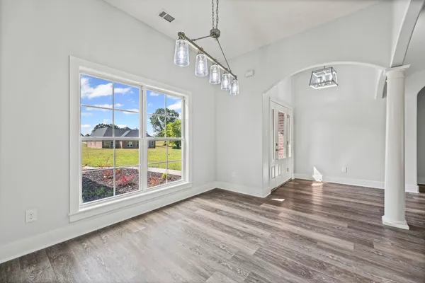 an empty room with wooden floor cabinet and windows