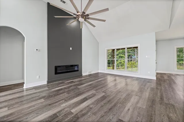 an empty room with wooden floor fan and windows