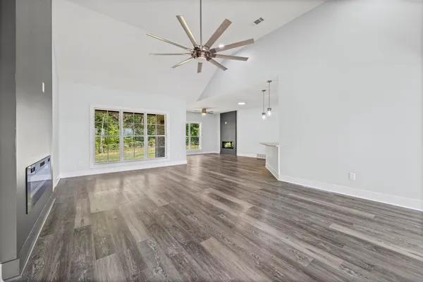 an empty room with wooden floor fan and windows