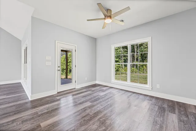 a view of an empty room with a window and wooden floor