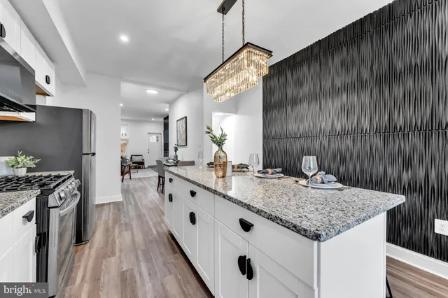 a kitchen with stainless steel appliances granite countertop a sink dishwasher stove and refrigerator with wooden floor