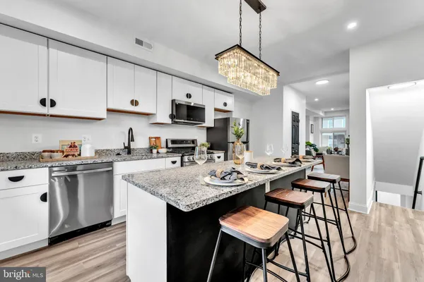 a kitchen with stainless steel appliances granite countertop a stove top oven a sink a refrigerator and white cabinets