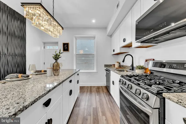 a kitchen with kitchen island granite countertop a sink stove and cabinets