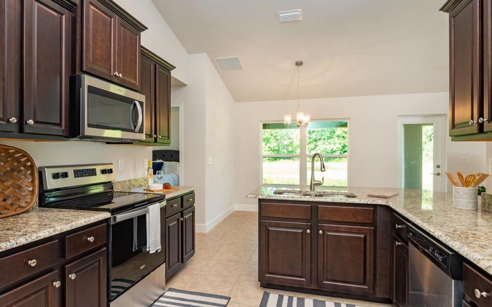 551 Quarry Lane Sebastian, FL 32958 - Photo 16 of 23 a kitchen with granite countertop a sink wooden cabinets and stainless steel appliances