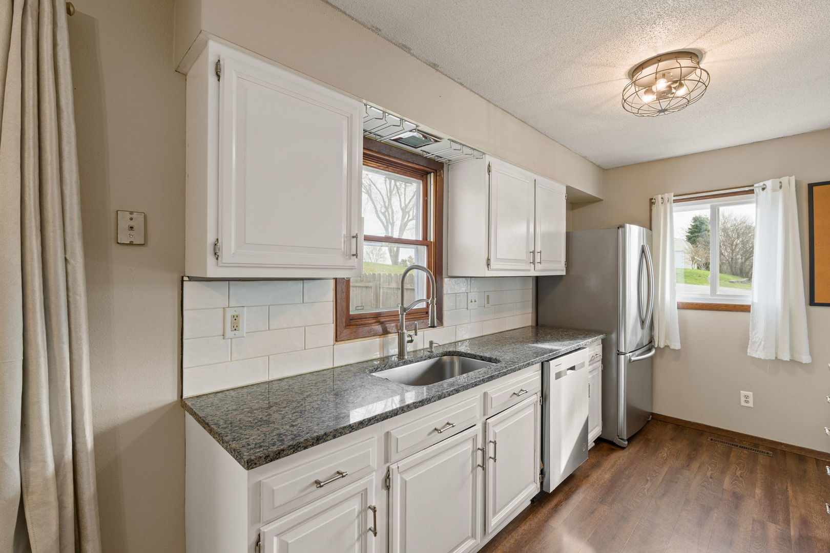 214 South 3rd Street Le Claire, IA 52753 - Photo 13 of 40 a kitchen with stainless steel appliances granite countertop a sink dishwasher a refrigerator and white cabinets with wooden floor