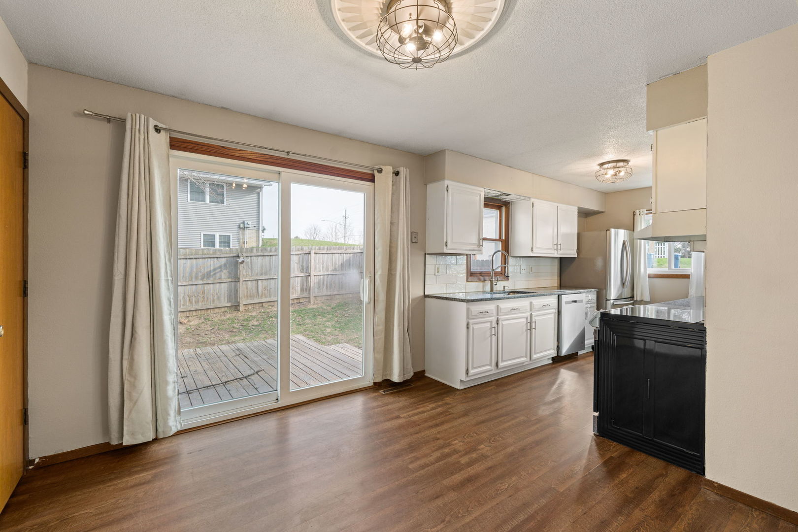 214 South 3rd Street Le Claire, IA 52753 - Photo 10 of 40 a kitchen with stainless steel appliances wooden floors and white cabinets