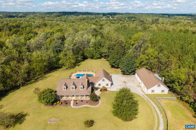 a aerial view of a house with swimming pool and large trees