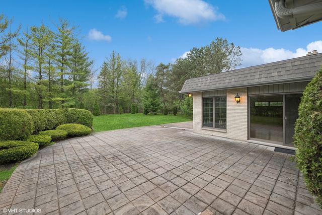 a view of yellow house with a yard and potted plants