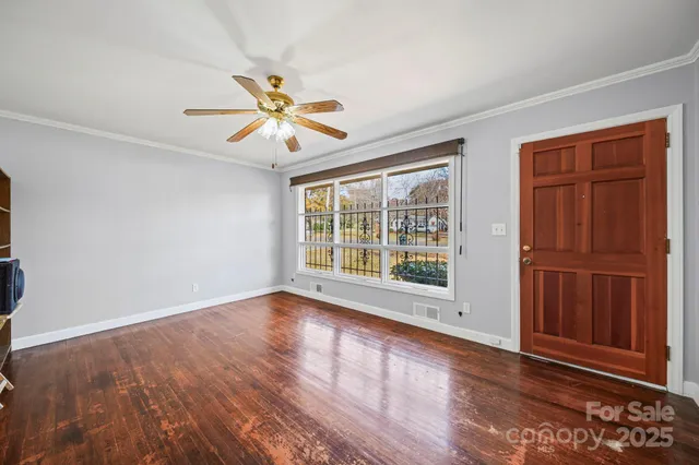 a view of an empty room with a window and wooden floor