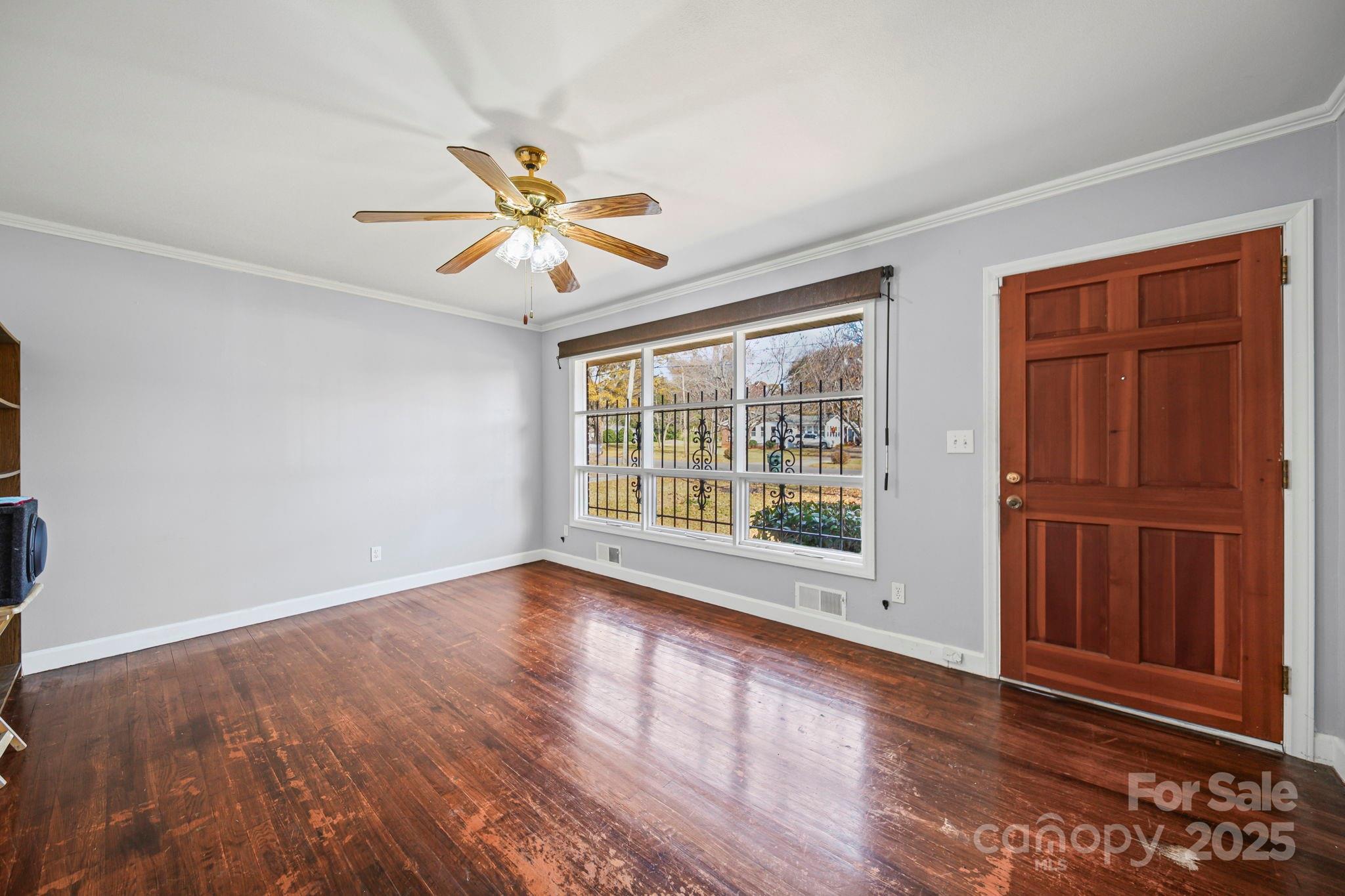 1703 East Perry Street Gastonia, NC 28054 - Photo 2 of 30 a view of an empty room with a window and wooden floor