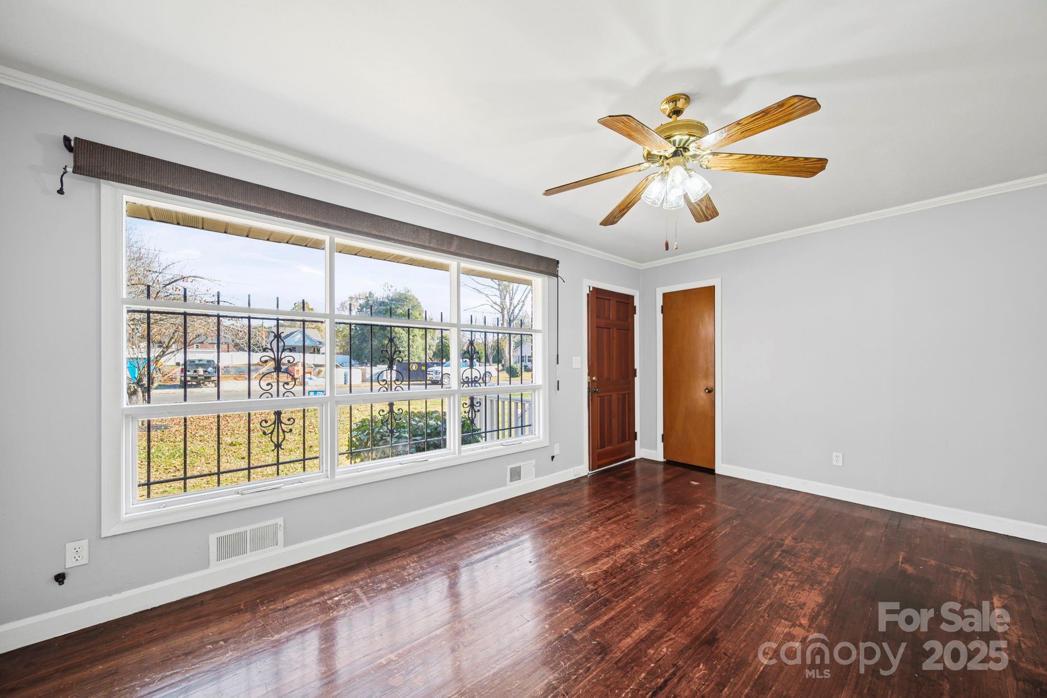 1703 East Perry Street Gastonia, NC 28054 - Photo 3 of 30 a view of an empty room with wooden floor and a window