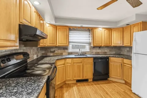 a kitchen with granite countertop wooden cabinets stove top oven and sink