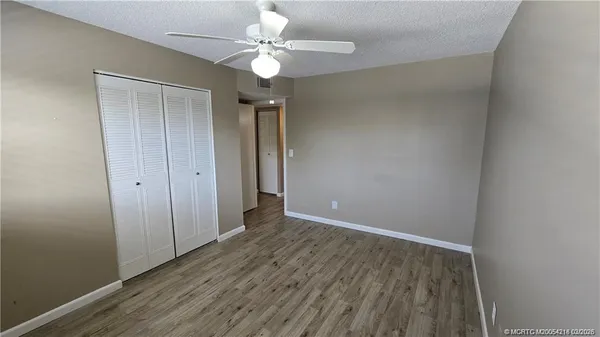 an empty room with wooden floor fan and window