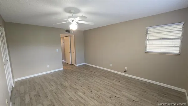 a view of an empty room with wooden floor and a window