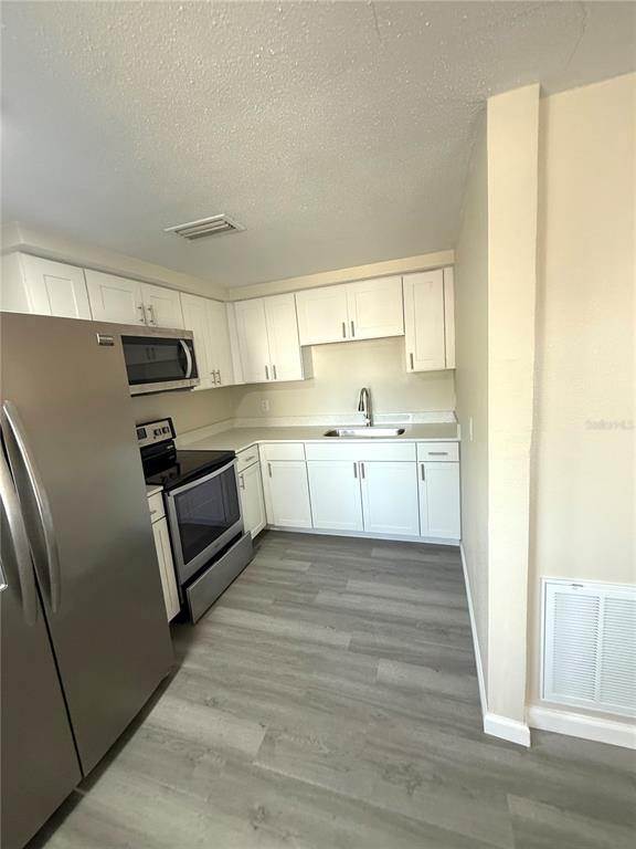 5318 Cedar Lane New Port Richey, FL 34652 - Photo 30 of 32 a kitchen with white cabinets and stainless steel appliances