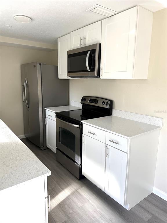 5318 Cedar Lane New Port Richey, FL 34652 - Photo 8 of 32 a kitchen with stainless steel appliances white cabinets and a stove top oven