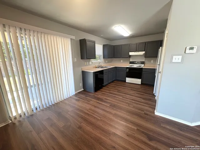 a large kitchen with stainless steel appliances wooden floor and a large window