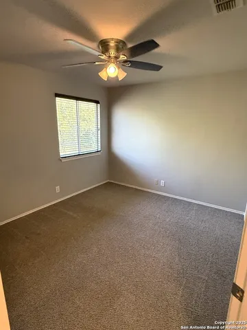 an empty room with a chandelier fan and windows