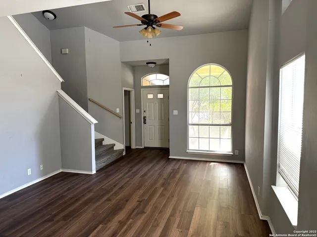 a view of empty room with wooden floor and fan