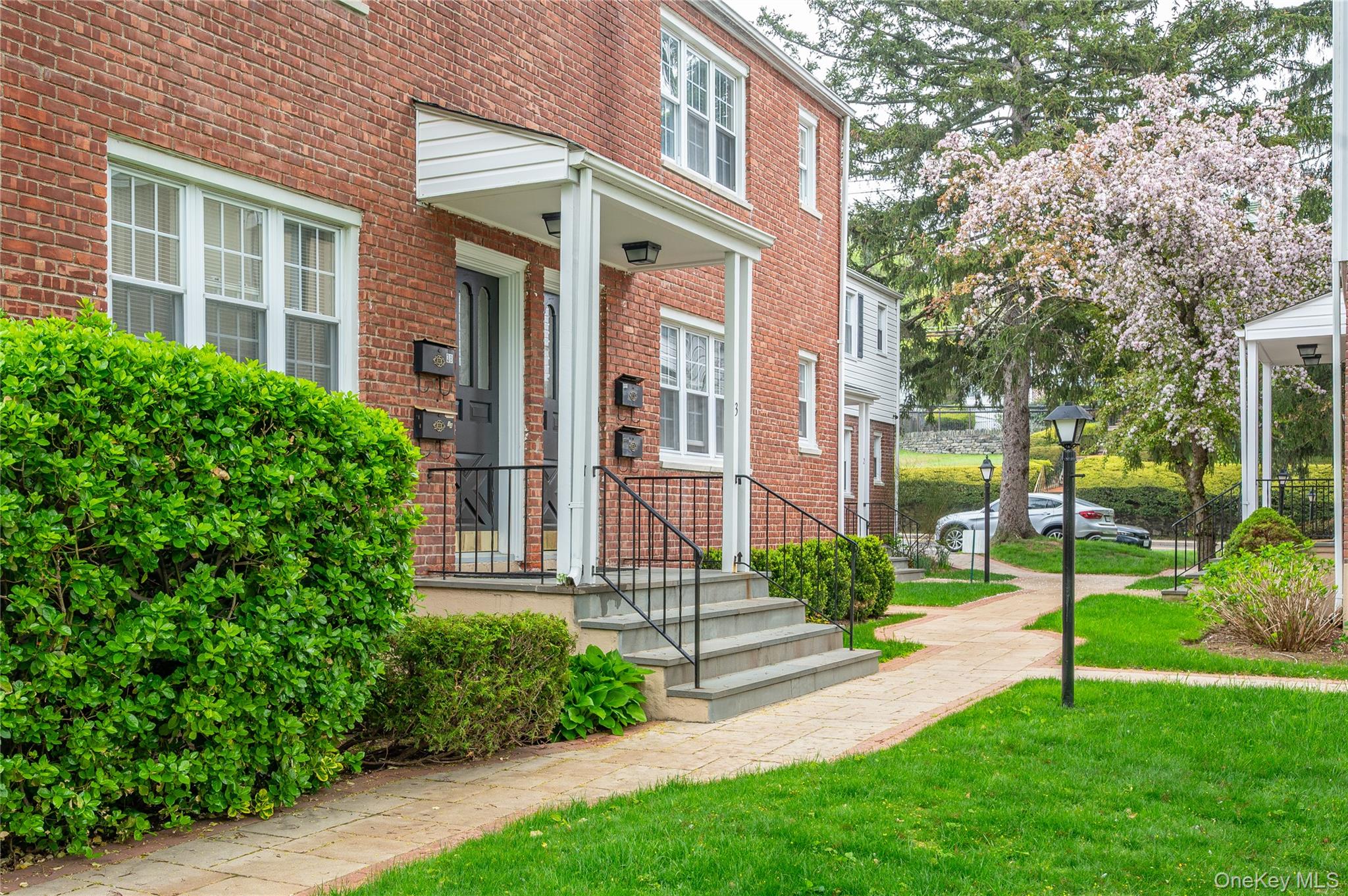 51 Cross Street, Unit 3B Yonkers, NY 10708 - Photo 15 of 18 Brick facade residences featuring white-framed windows, individual entryways with covered porches, and black wrought iron railings