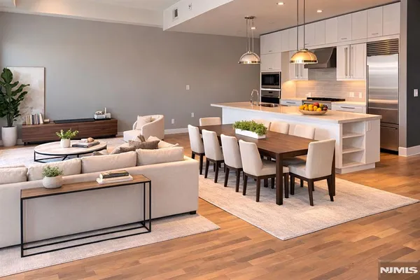 a kitchen with stainless steel appliances kitchen island granite countertop a table chairs and a refrigerator