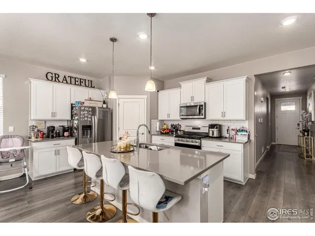 a kitchen with stainless steel appliances kitchen island granite countertop a sink refrigerator and cabinets