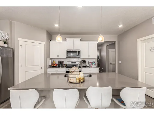 a kitchen with stainless steel appliances kitchen island granite countertop a refrigerator a stove a sink dishwasher and white cabinets with wooden floor