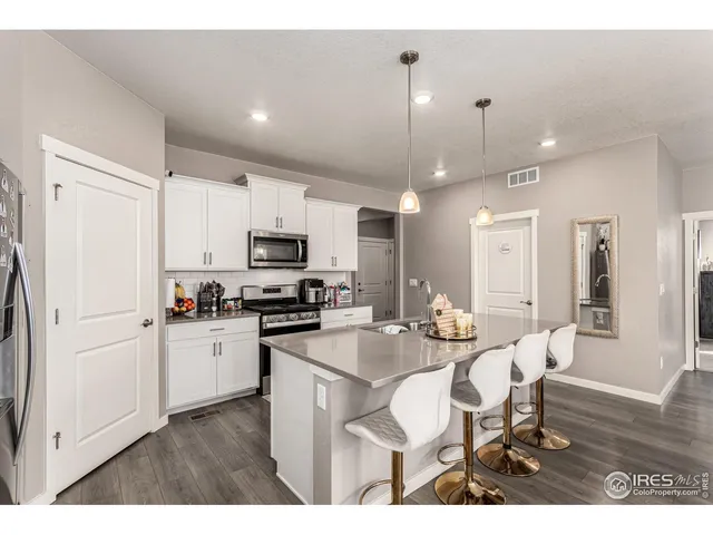 a kitchen with stainless steel appliances kitchen island granite countertop a refrigerator a stove a sink a dining table and chairs with wooden floor