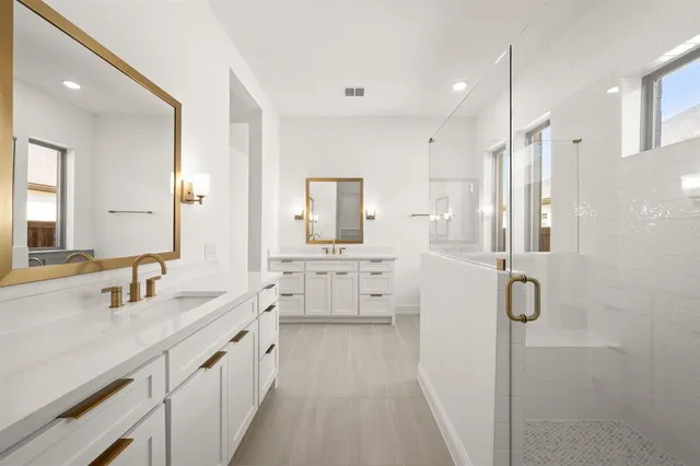 a bathroom with a double vanity sink mirror and shower