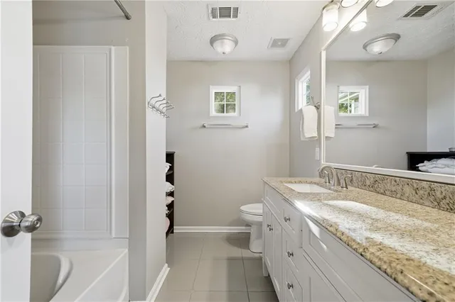 a bathroom with a granite countertop sink a toilet and shower