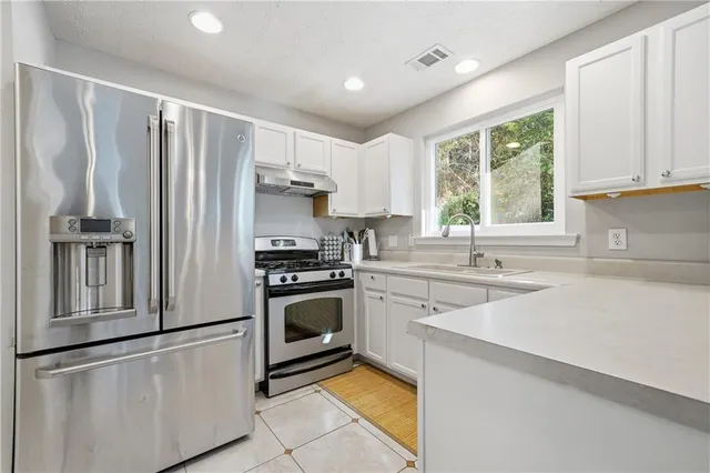 a kitchen with granite countertop a refrigerator stove top oven and sink