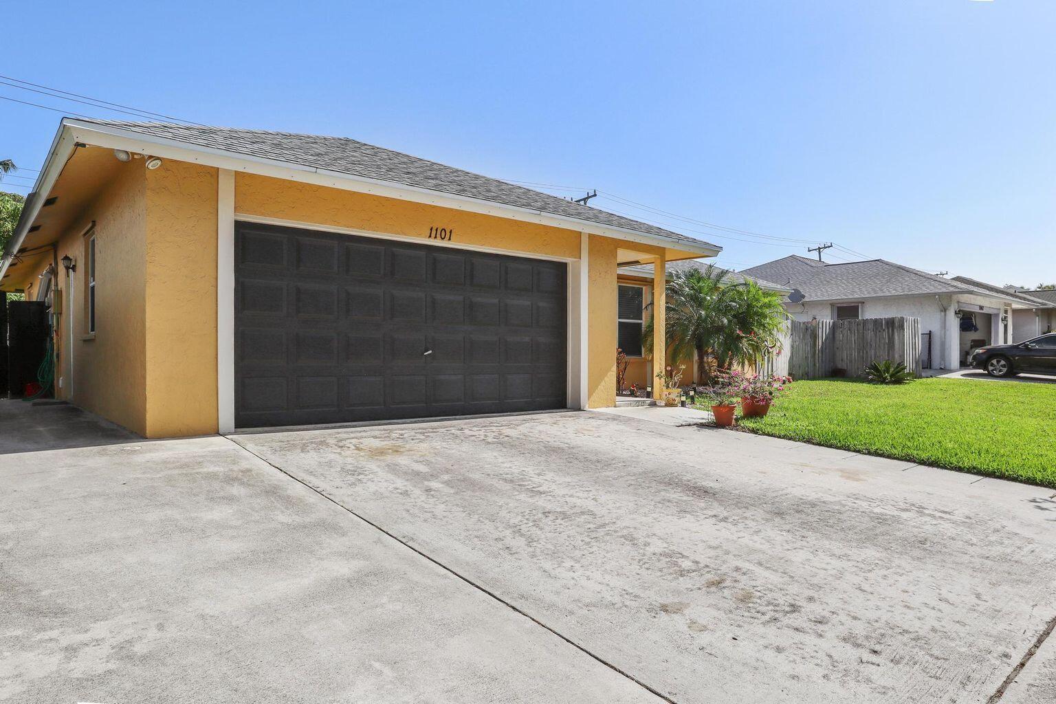 1101 Julia Heights Drive Lantana, FL 33462 - Photo 2 of 19 a front view of a house with a yard and garage