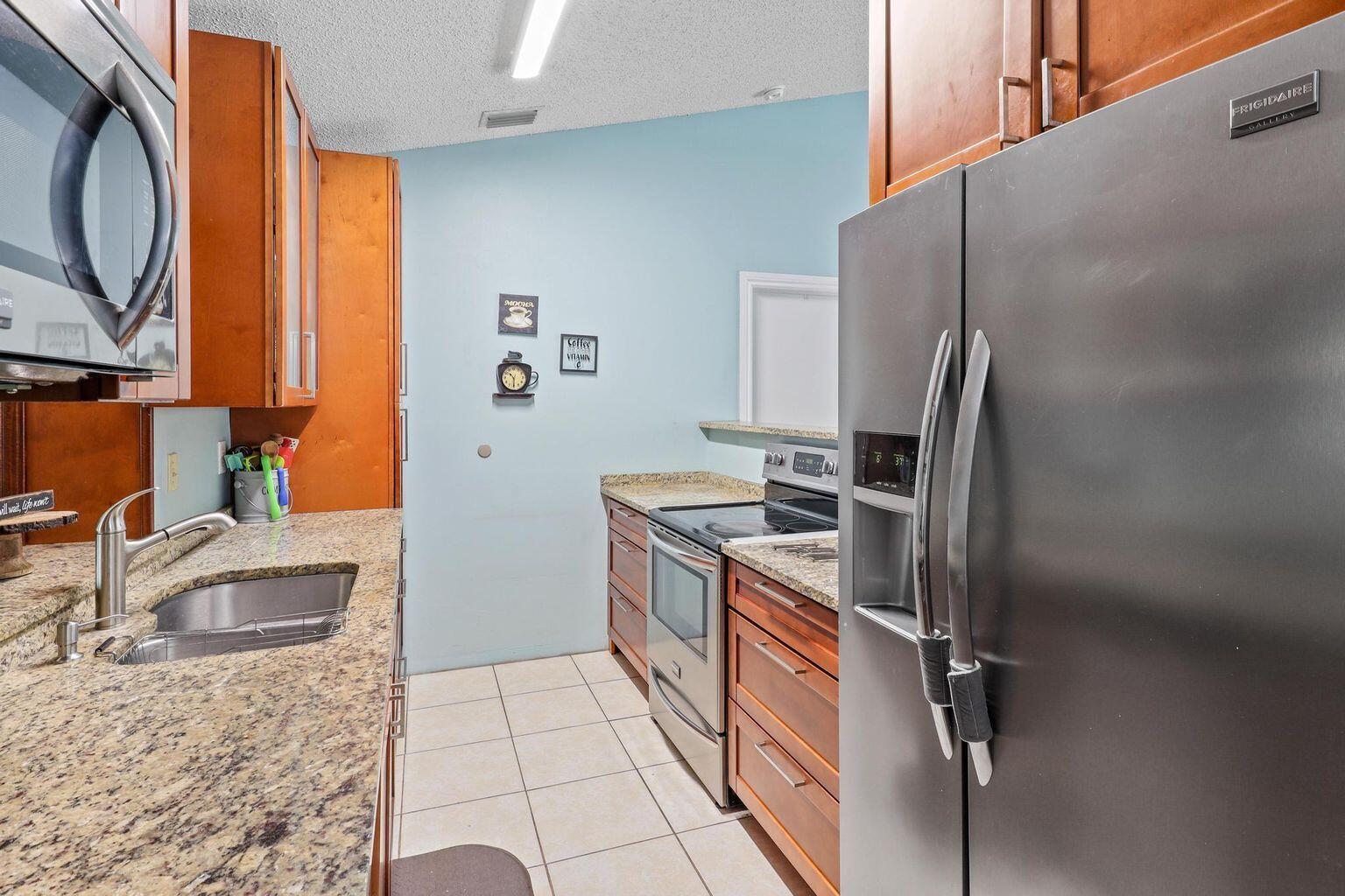 1101 Julia Heights Drive Lantana, FL 33462 - Photo 6 of 19 a kitchen with stainless steel appliances granite countertop a sink stove and refrigerator