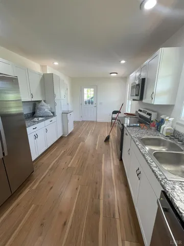 a kitchen with granite countertop a sink a counter top space stainless steel appliances and cabinets