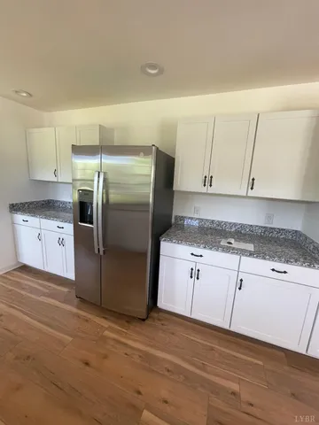 a kitchen with granite countertop a refrigerator and cabinets