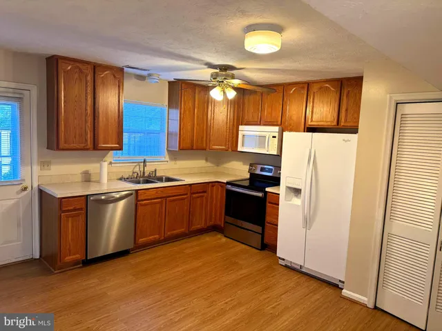 a kitchen with stainless steel appliances granite countertop a refrigerator a sink dishwasher a stove with wooden floor and cabinets