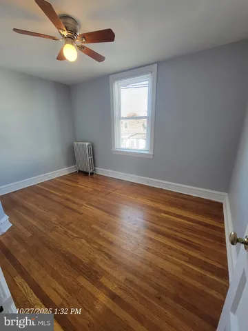 a view of an empty room with window and chandelier fan