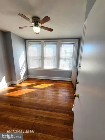 a view of empty room with wooden floor and fan