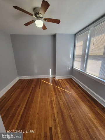 an empty room with wooden floor fan and windows