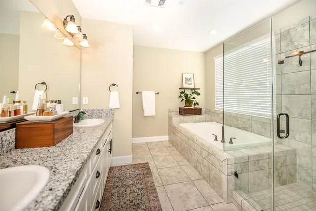 a spacious en suite bathroom with a double sink and mirror