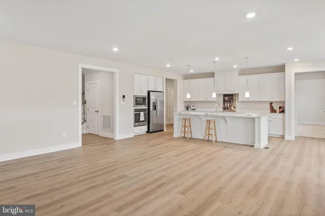 a view of kitchen with stainless steel appliances granite countertop a stove top oven a refrigerator a sink and a large window with wooden floor