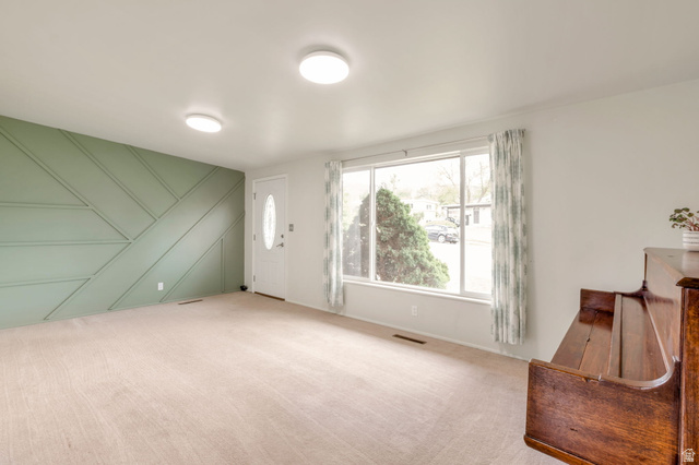 447 550 South Bountiful, UT 84010 - Photo 2 of 25 Spacious living area featuring a decorative accent wall, a white entry door with an oval glass insert, and large picture windows