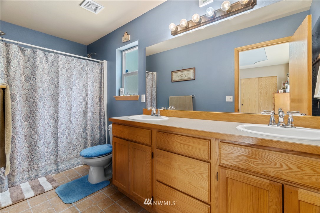 5037 180th Trail Southwest Rochester, WA 98579 - Photo 14 of 38 a bathroom with a sink a toilet a mirror and shower curtain