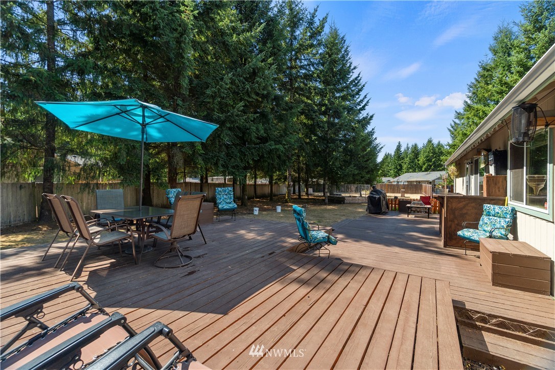 5037 180th Trail Southwest Rochester, WA 98579 - Photo 20 of 38 a view of a patio with table and chairs under an umbrella with wooden floor