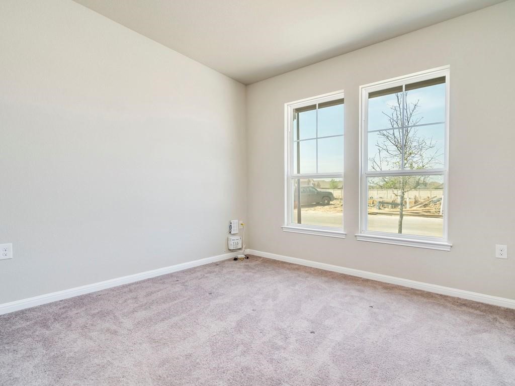4210 Birdwatch Loop, Unit 2 Pflugerville, TX 78660 - Photo 21 of 31 Natural light streams into this versatile space, featuring neutral carpeting and clean walls.