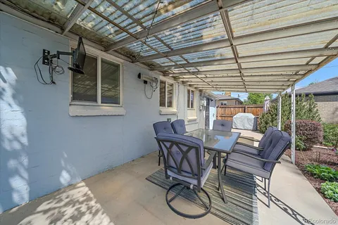 a view of a patio with table and chairs with wooden floor and fence