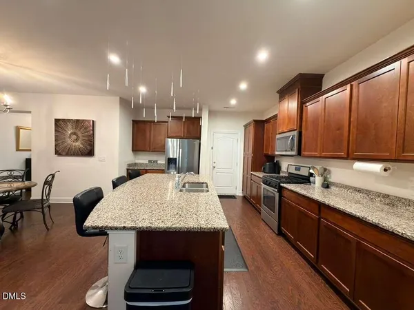 a kitchen with stainless steel appliances granite countertop a stove refrigerator a sink dishwasher and microwave with wooden floor