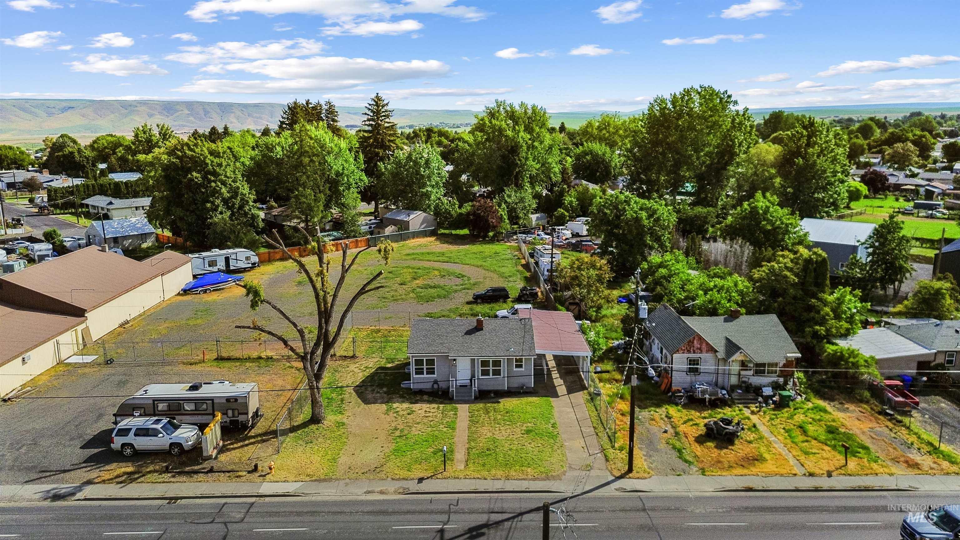 619 Thain Road Lewiston, ID 83501 - Photo 43 of 44 Expansive property lot featuring two single-story residences, a large undeveloped grassy area, and a paved commercial-style parking area with a fenced perimeter